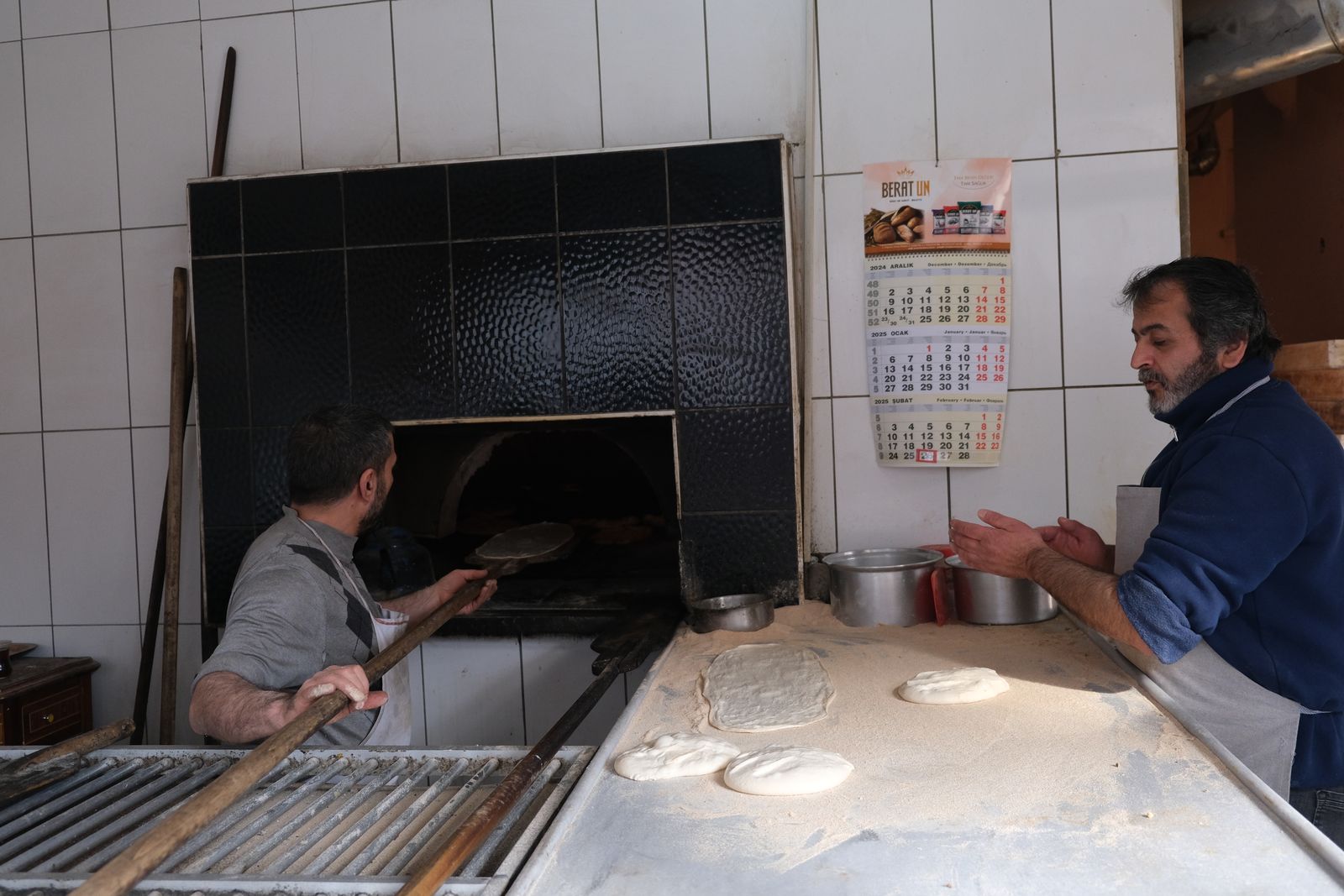 Bakers working an oven with a production calendar on the wall, the heart of bakery operations run on a schedule